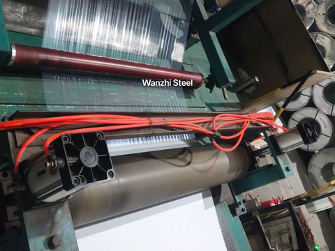 The steel coil is being coated with a protective film.